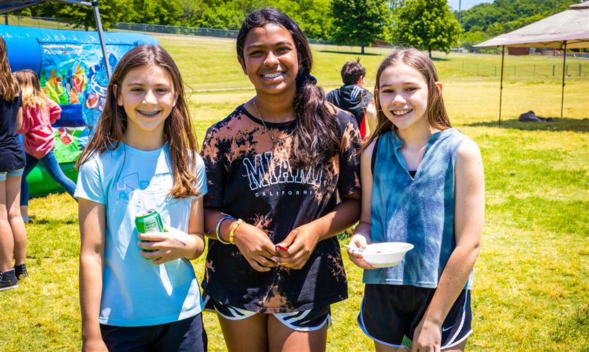 Three girls smile while outside
